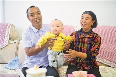<p>　　劉克瑞（左）和妻子在客廳中陪孫子玩耍。　均本報記者　馬楠　攝</p>